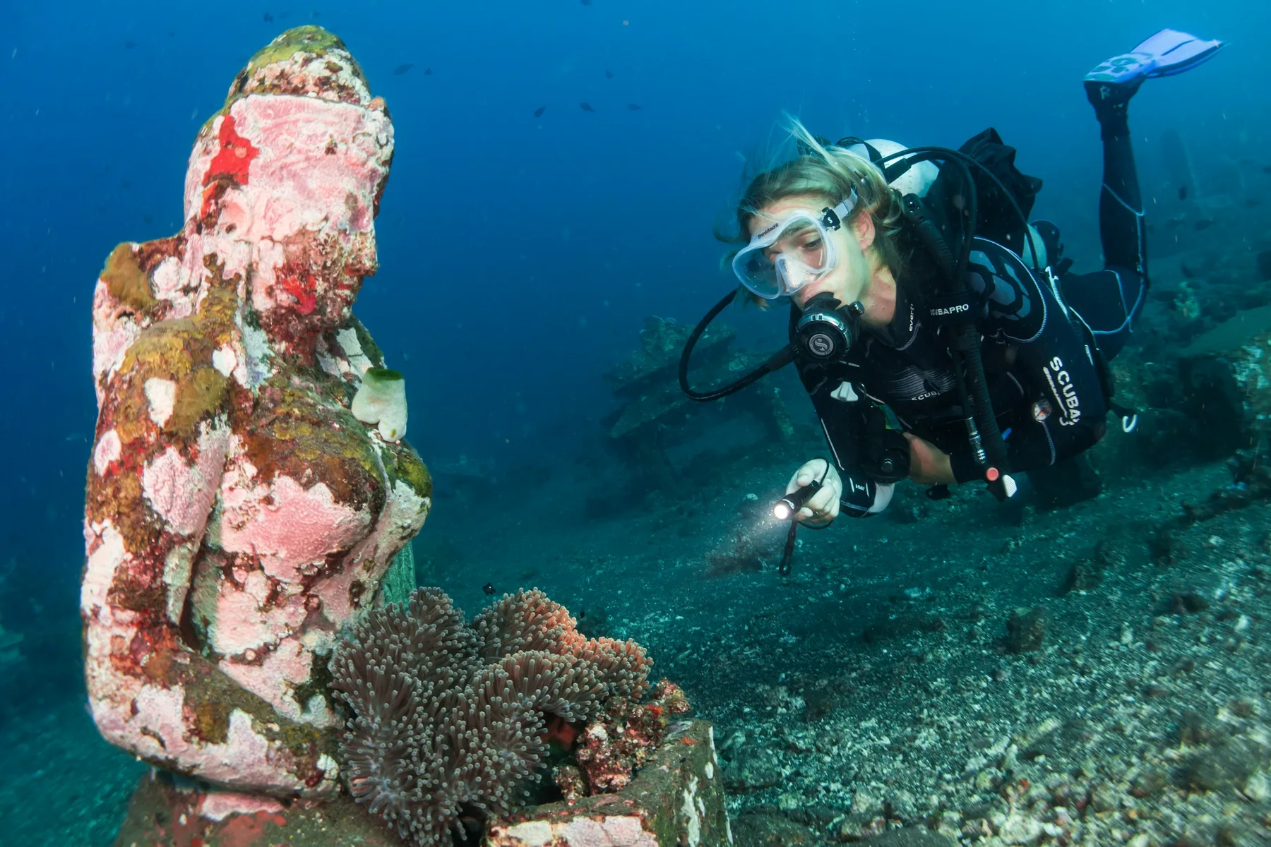 A scuba diver explores beside an underwater statue in Bali.